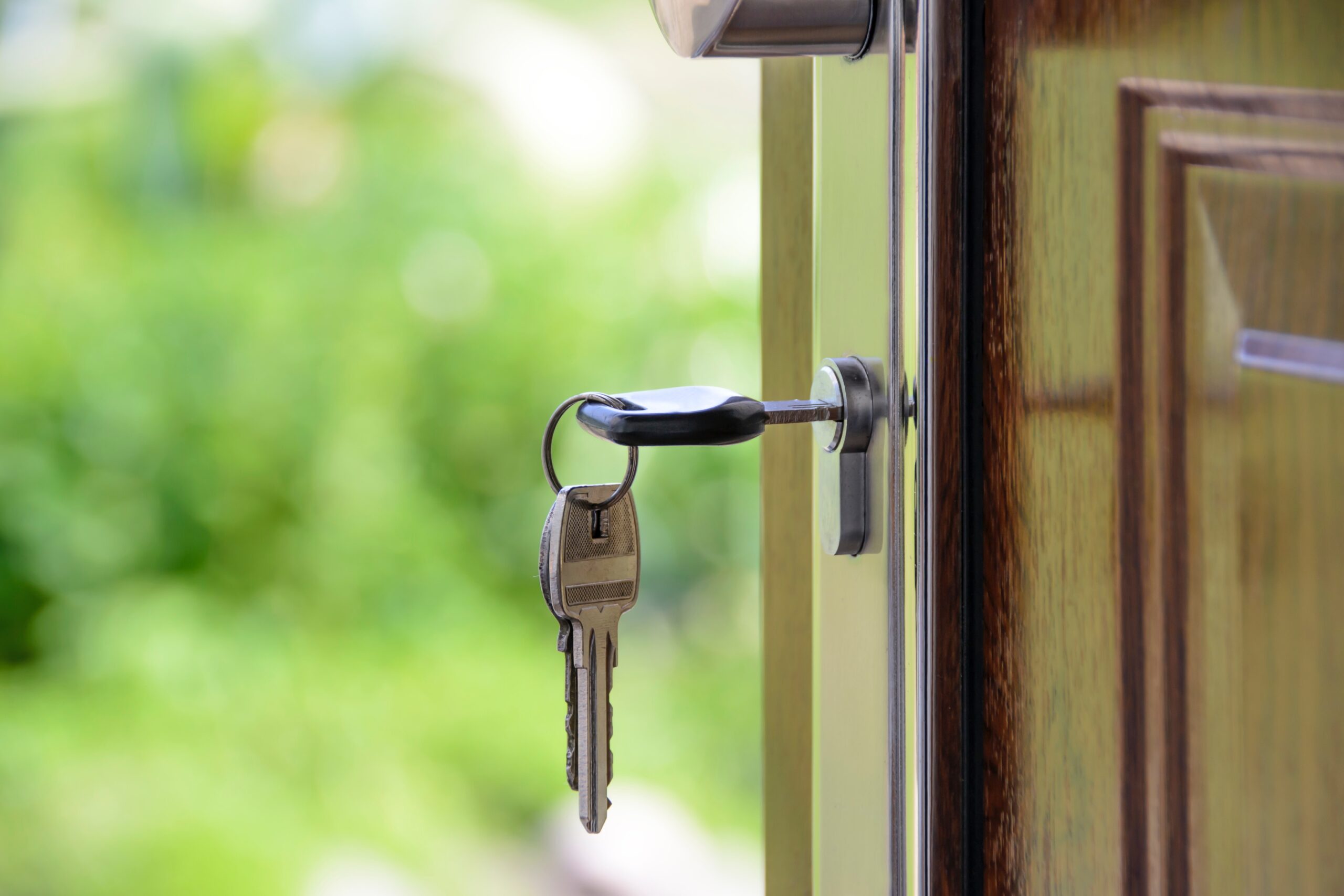 Key in door lock symbolizing home ownership and mortgage pre-approval process, with blurred greenery background.