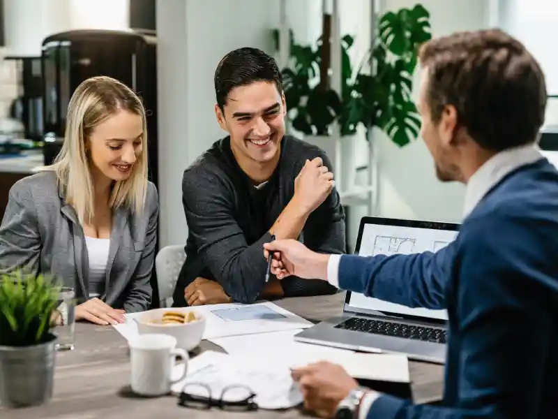 Couple discussing Jumbo Loan options with a financial advisor in a modern office setting, showcasing personalized service for homebuyers in Elk Grove, CA.