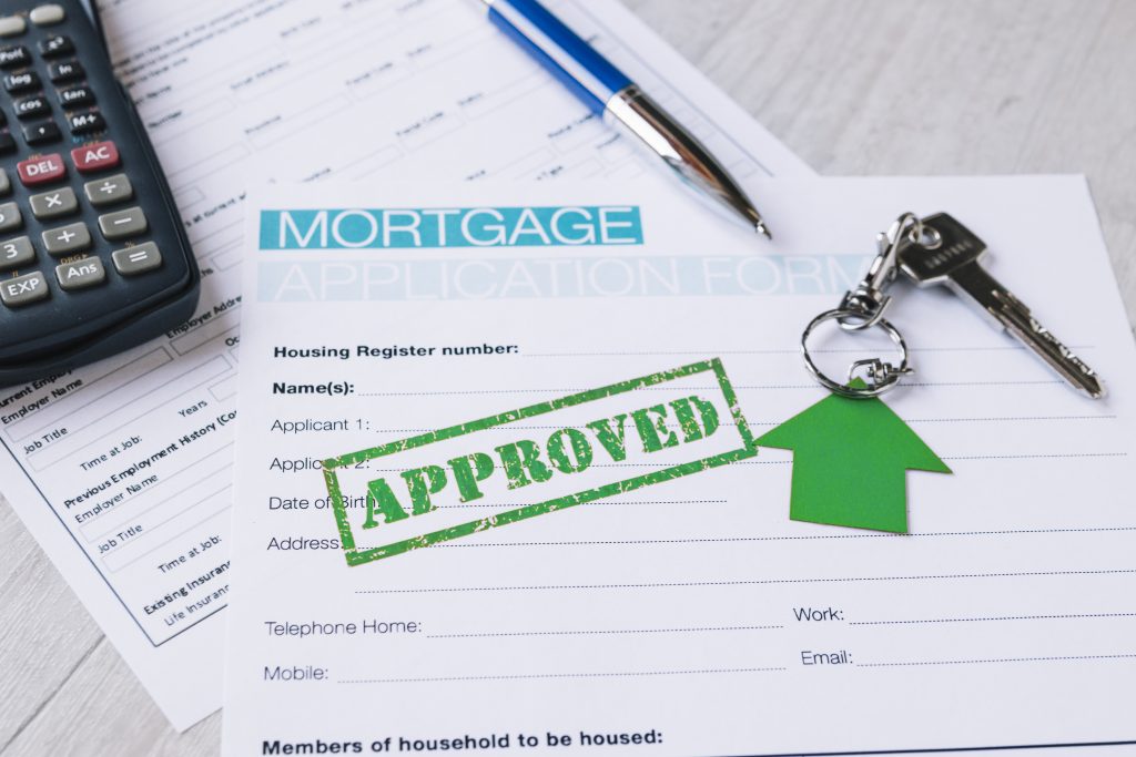 Mortgage application form with "APPROVED" stamp, keys, calculator, and pen, illustrating the pre-approval process in home loans.
